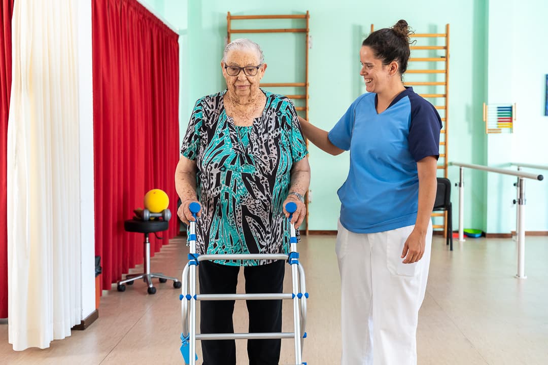 Cuidador ayudando a adulto mayor con ejercicios de movilidad y alimentación